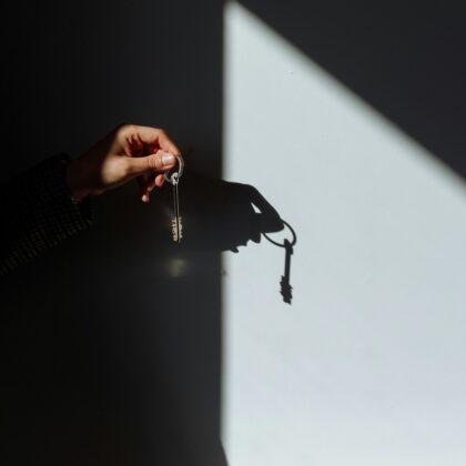 Minimalist photo of a hand holding a key casting a shadow, signifying property ownership